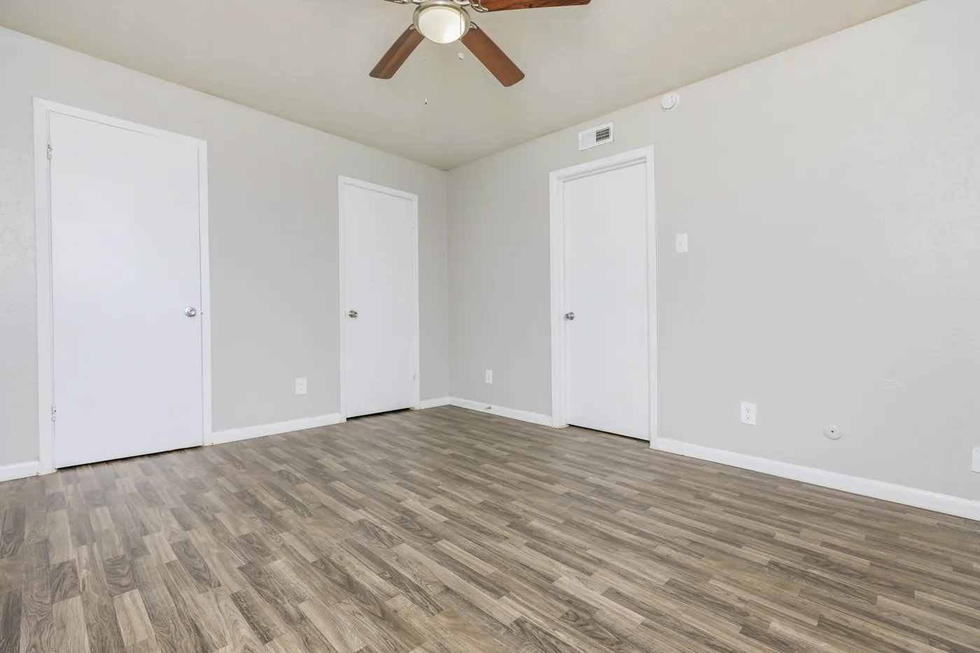 Bedroom with wood-look flooring and a row of closet doors