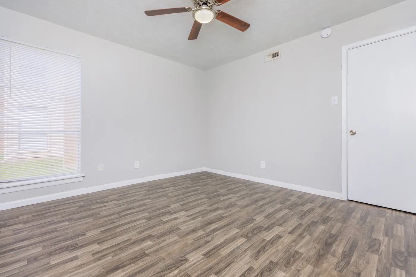 Bedroom with ceiling fan, blinded window, and wood-look flooring