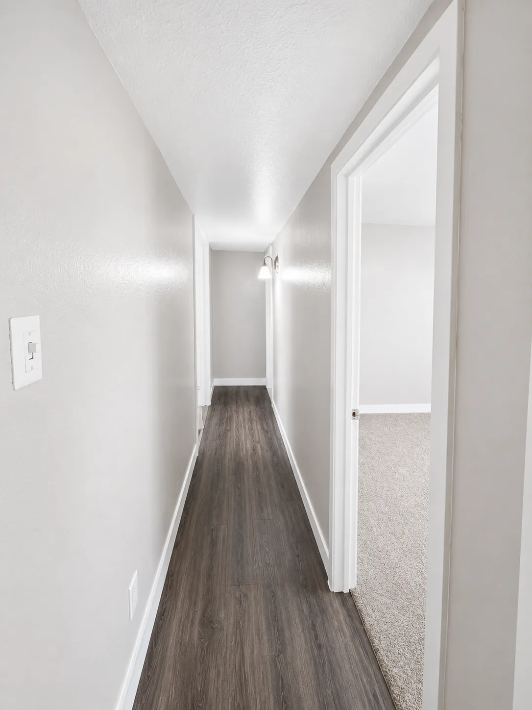 C1 hallway with wood-look flooring and a doorway through to a carpeted bedroom