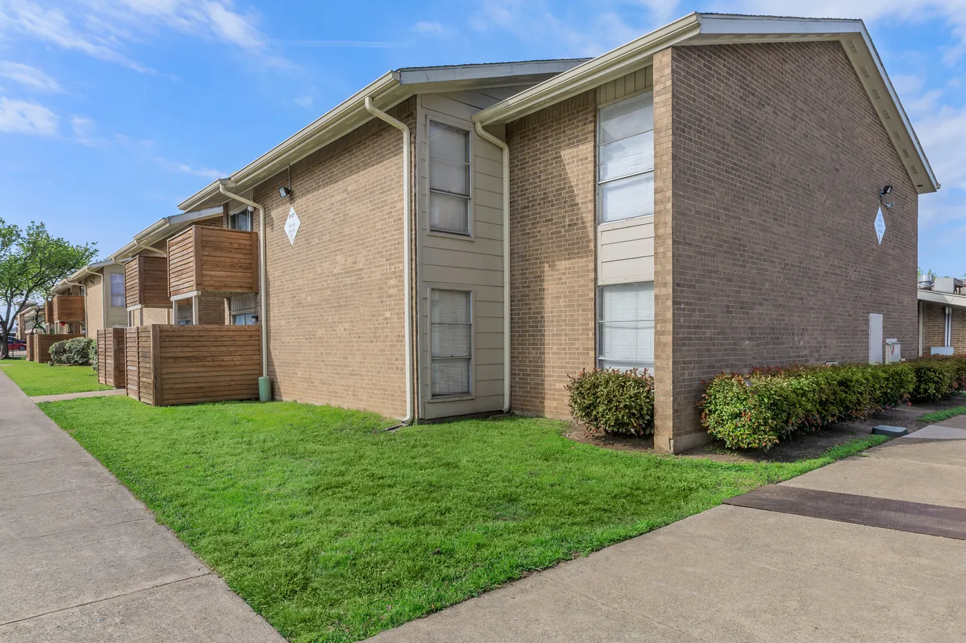 Brick building corner along the lawn with a sidewalk approach