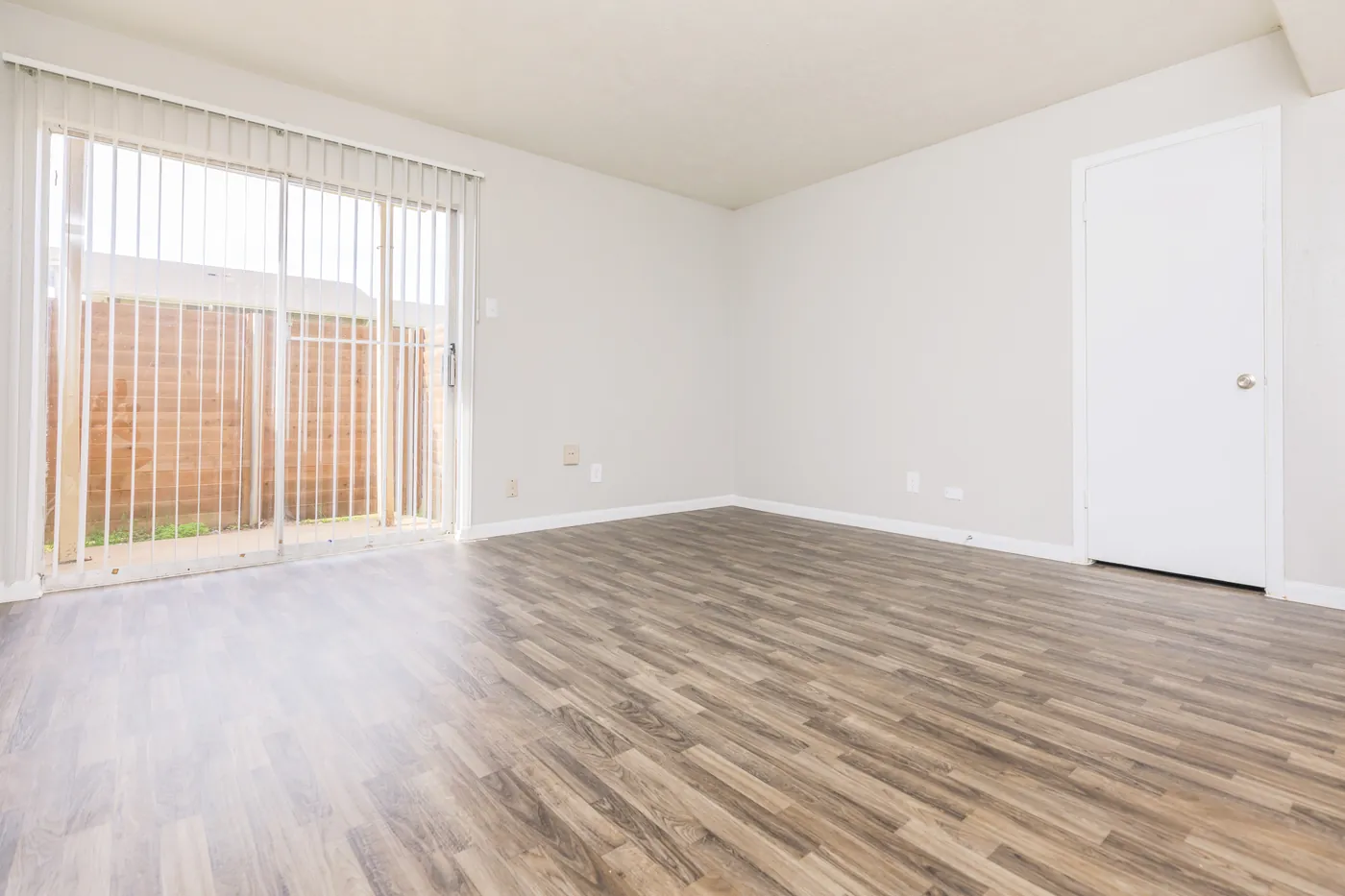 Living area with wood-look flooring and a sliding door to the private patio