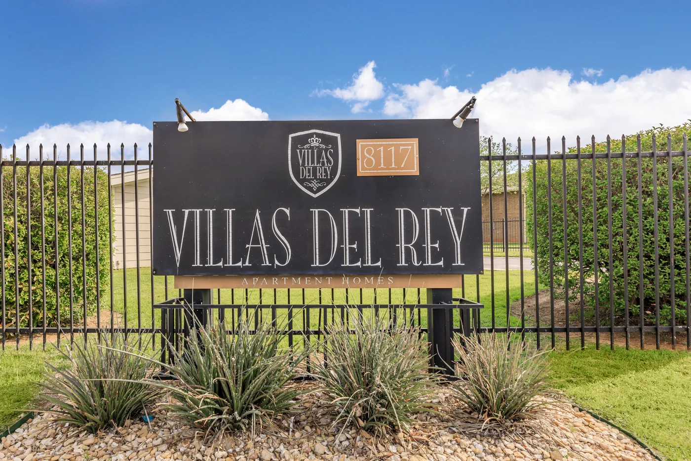 Villas Del Rey monument sign and crest behind the black perimeter fence