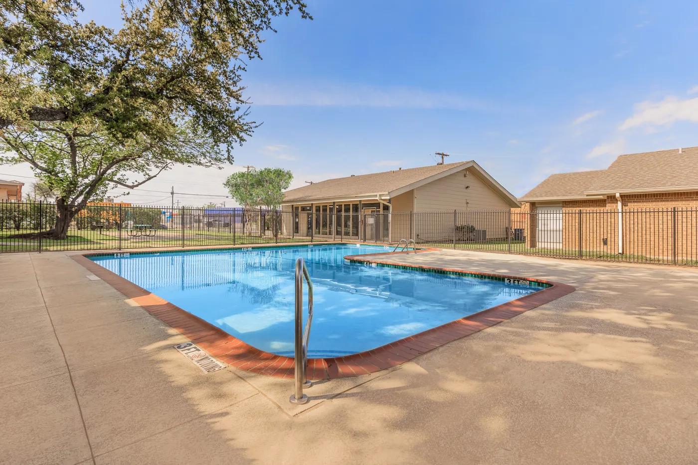 Swimming pool with red-brick coping beside the pool house